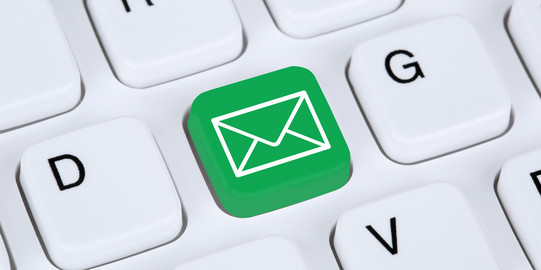 Email Eine weiße Tastatur im Detail. Eine Taste ist grün eingefärbt mit einem weißen Briefumschlag darauf.